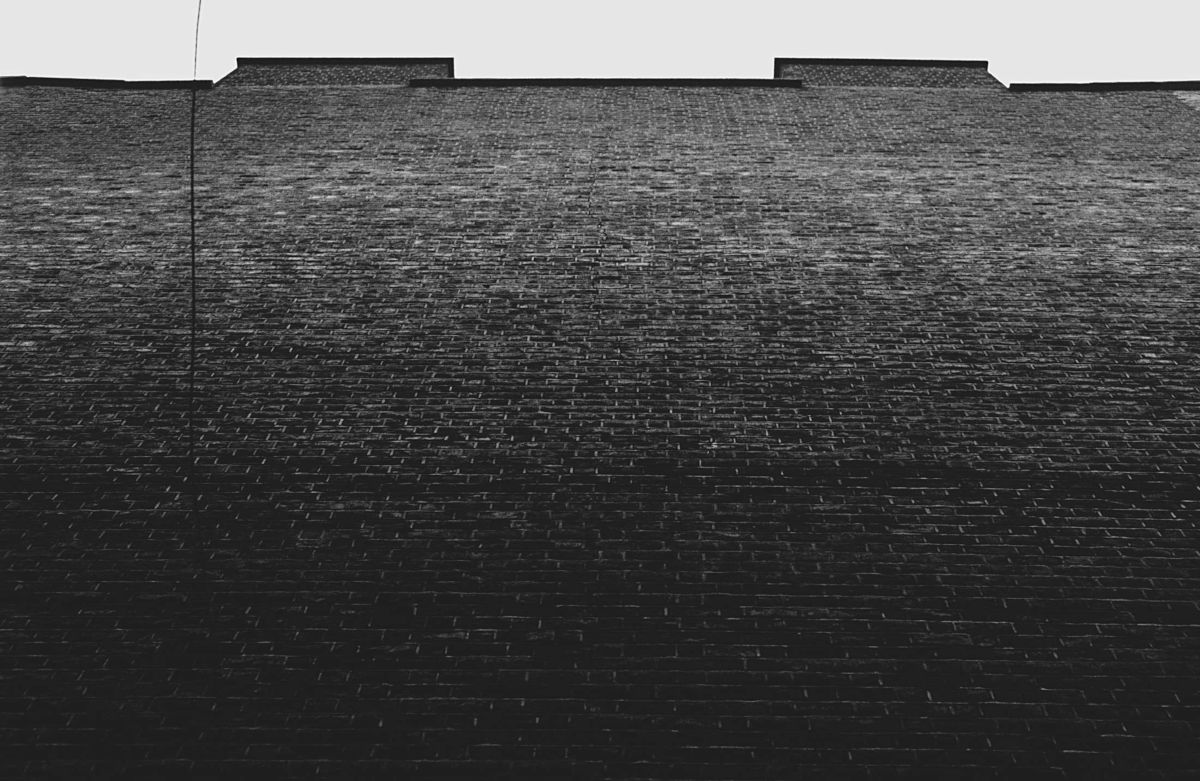 Black-and-white photo of a brick wall receding into gray sky